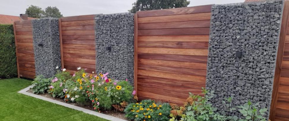 Houten schutting met schanskorven tussenstukken.