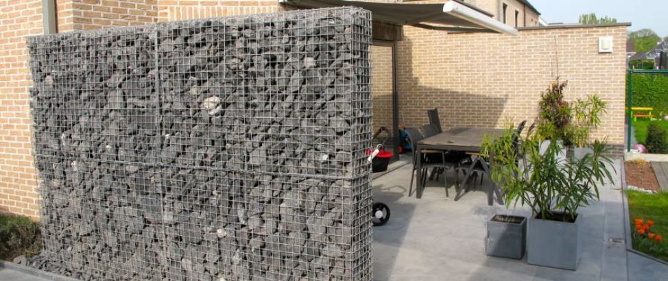 Een schanskorven tuinafscheiding naast een terras.
