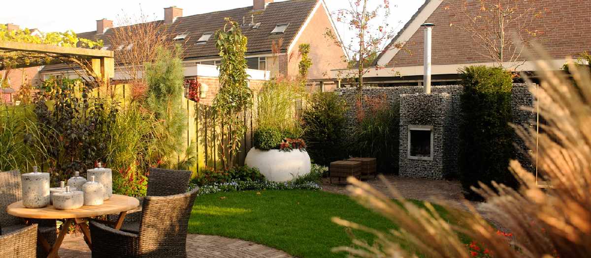 een groene tuin  met in de hoek een buitenhaard