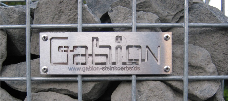 Gabion Schanskorven: dé specialist in schanskorven en toebehoren Ijzeren plaquetto met logo Gabion Schanskorven op een schanskorf gevuld met breukstenen.