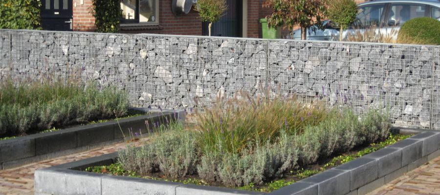 Steenkorven kopen voor een moderne en onderhoudsvrije tuin Strakke steenkorven gebruikt als afscheiding in een tuin met beplanting.